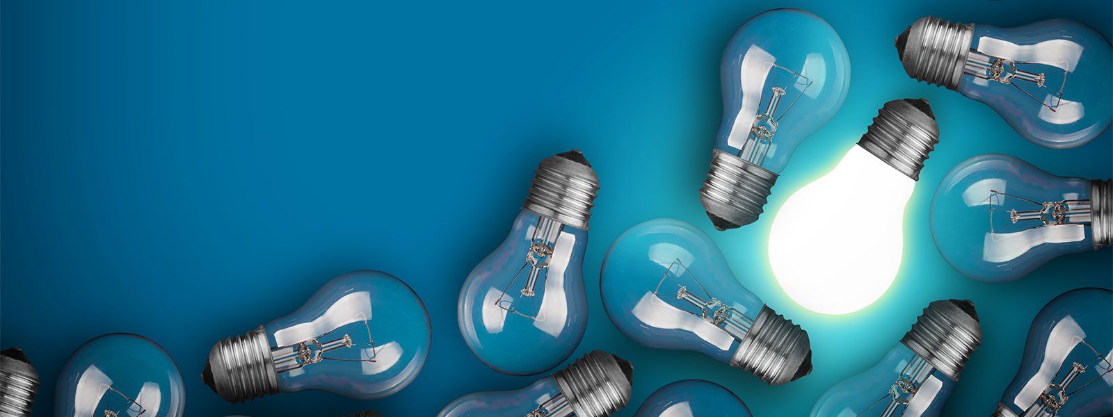 Glowing lightbulb among unlit bulbs on blue