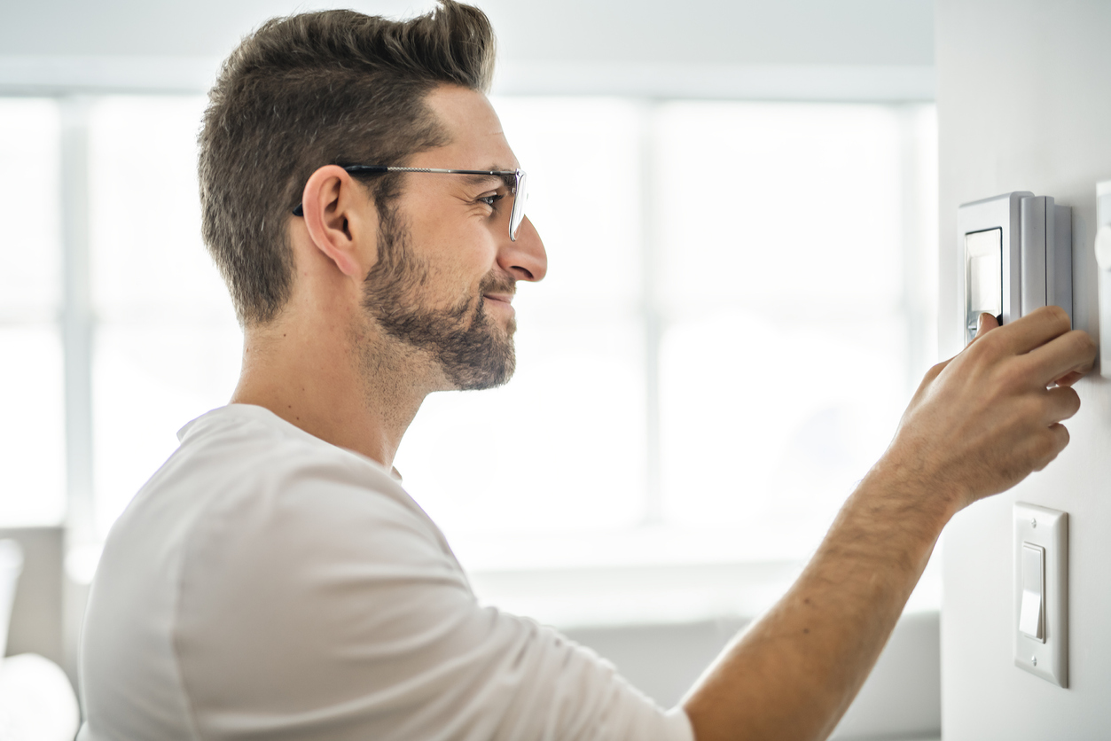 man adjusting his home thermostat