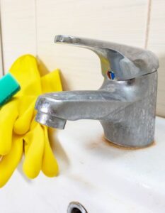 Yellow gloves next to a lime scale faucet