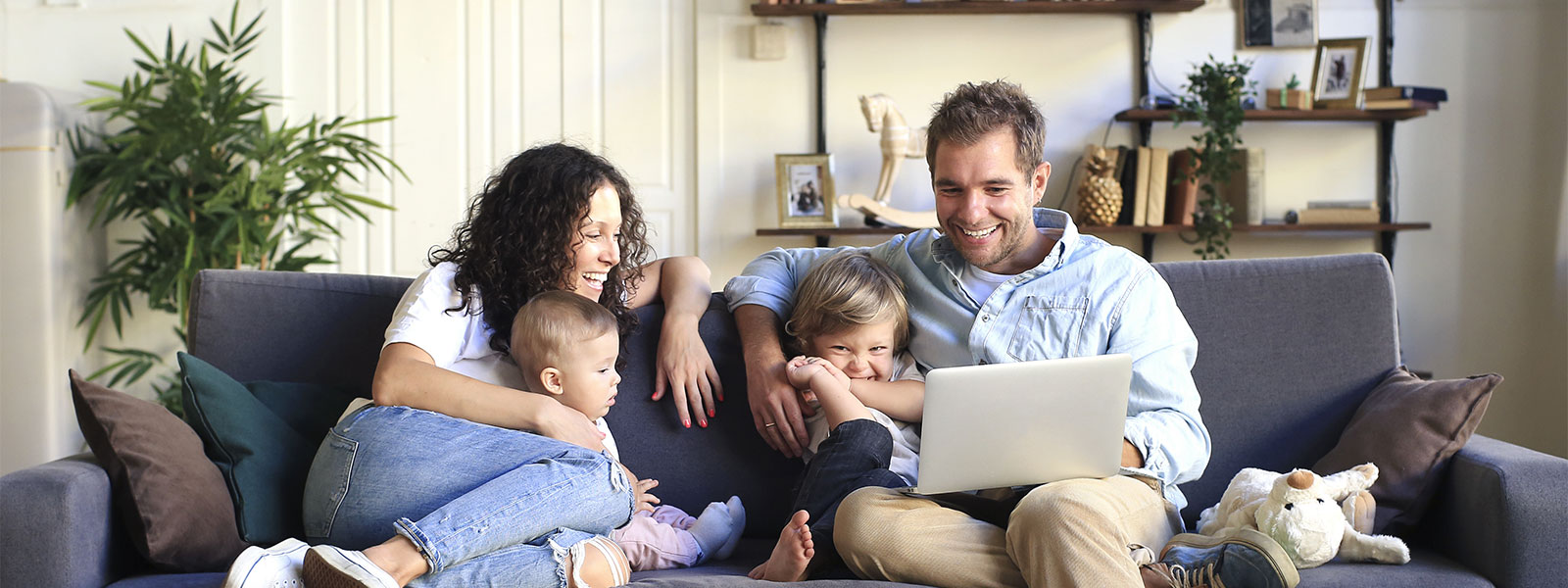 family laughing on a couch with a laptop computer