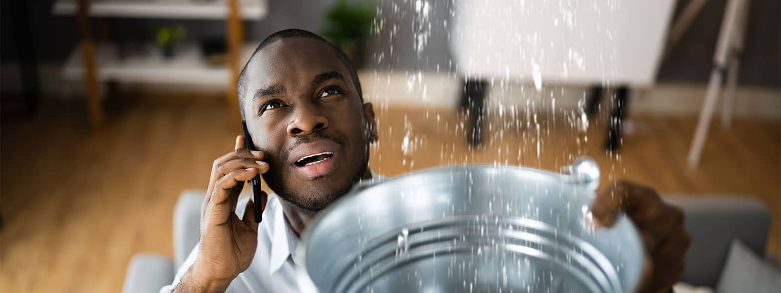 Man catching water leaking from ceiling
