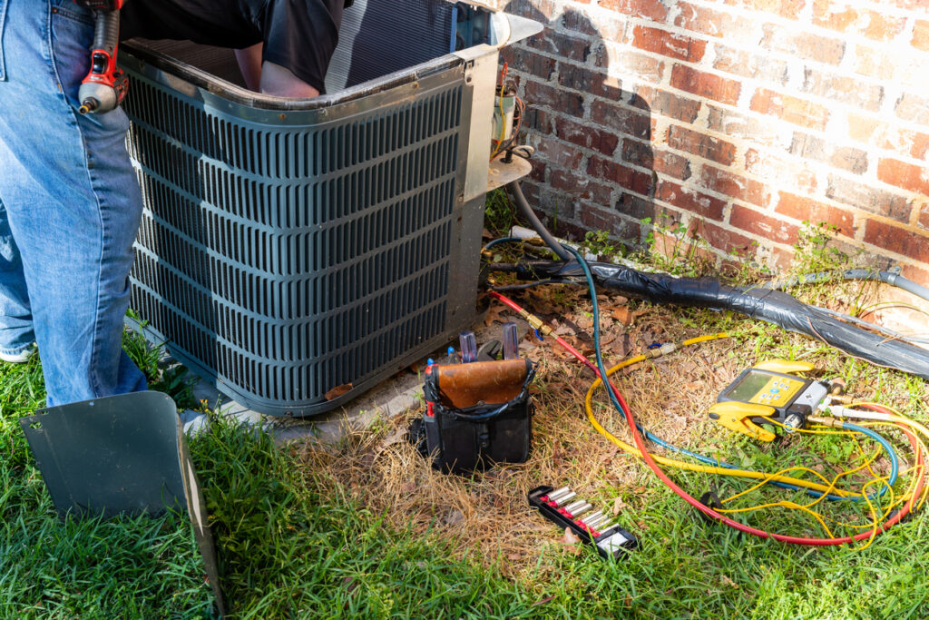 Outdoor air conditioner service with tools during HVAC repair. A Haller tech can help you decide whether to repair or replace your air conditioner