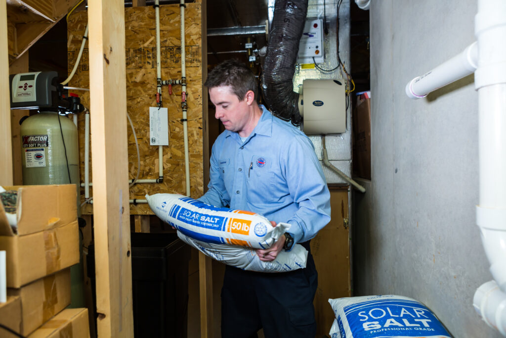 A Haller technician carries a bag of salt for a water softener system