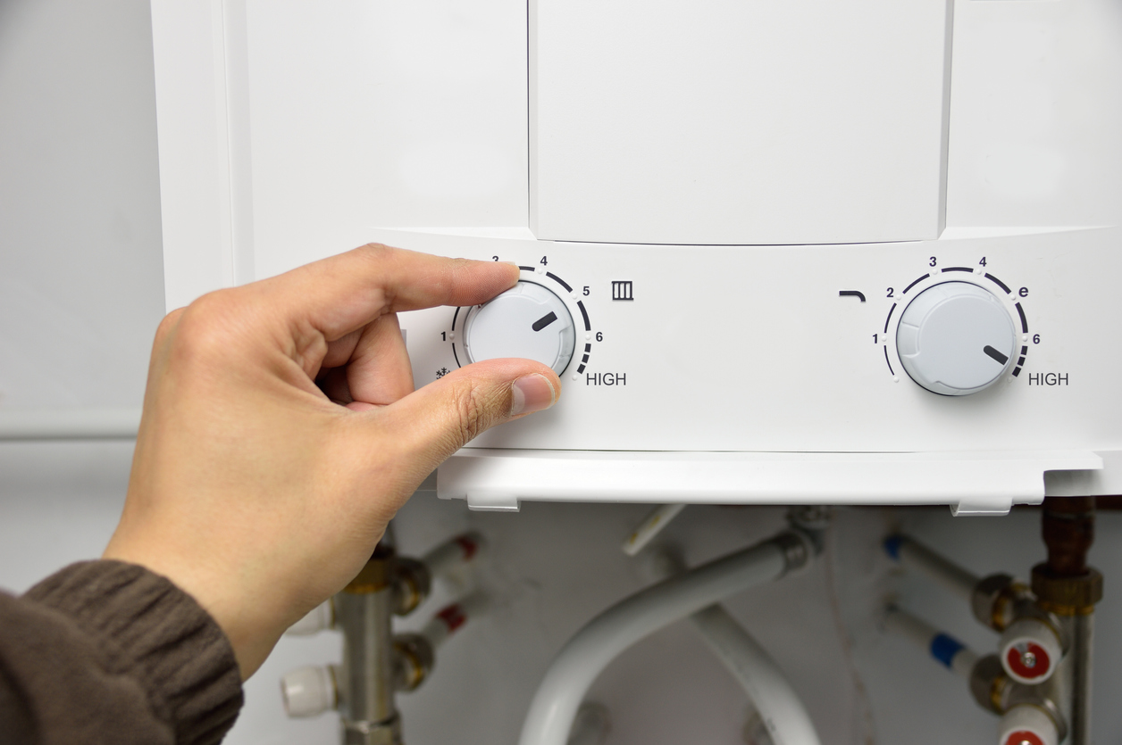 Woman's hand adjusting a knob on a water heater.