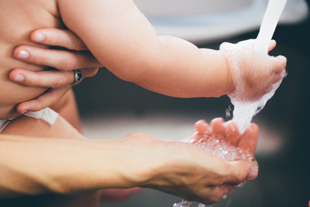 Close view of a mother and young child feeling water as it comes out of a faucet.