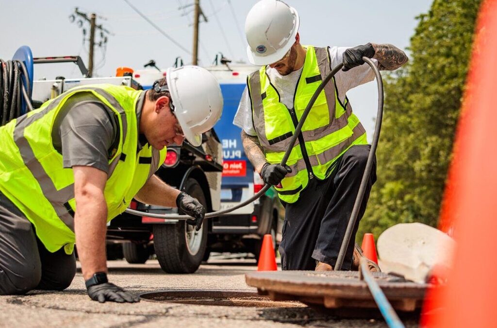 Image of two Haller technicians inspecting sewer and pipe system for drainage or other plumbing issues.