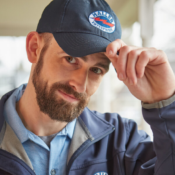 Haller technician holding brim of baseball cap and giving a little nod