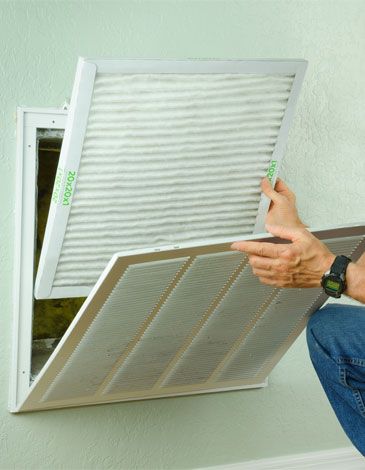 Man changing air conditioning filter in home