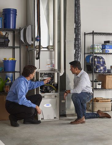 Installer and homeowner kneeling looking at new furnace