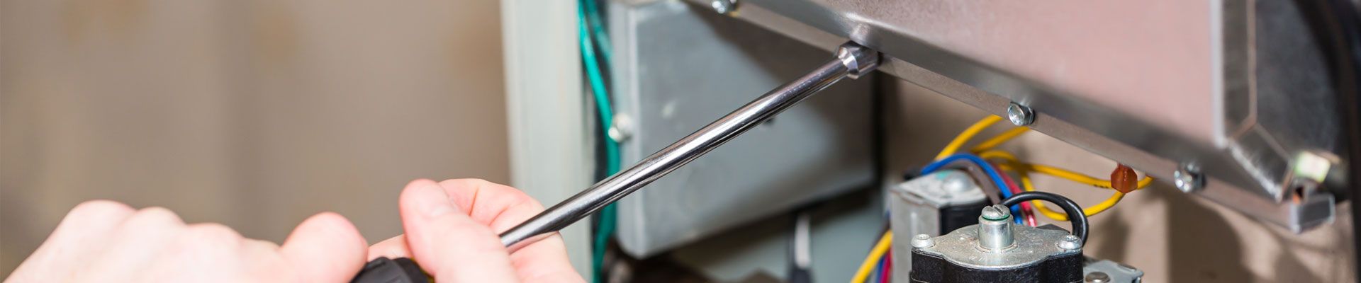 Technician using screwdriver to repair furnace close up