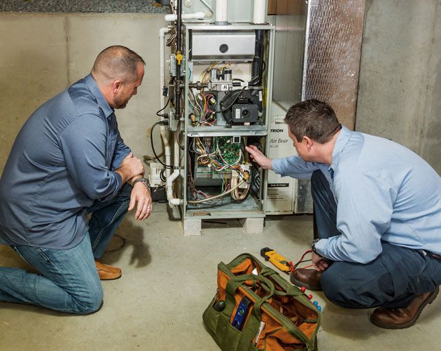 HVAC technician showing homeowner inside of furnace