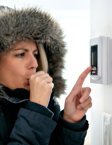 Woman in fur coat concerned about thermostat