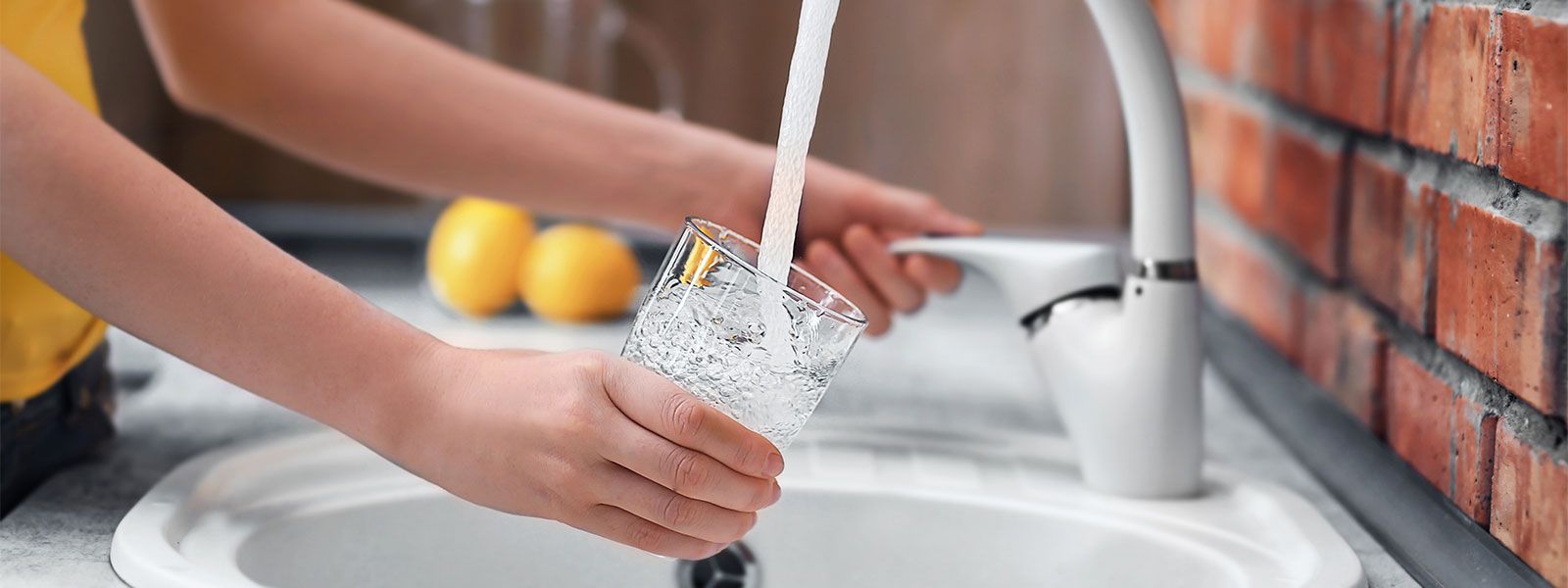 Woman filling glass from tap with clear water