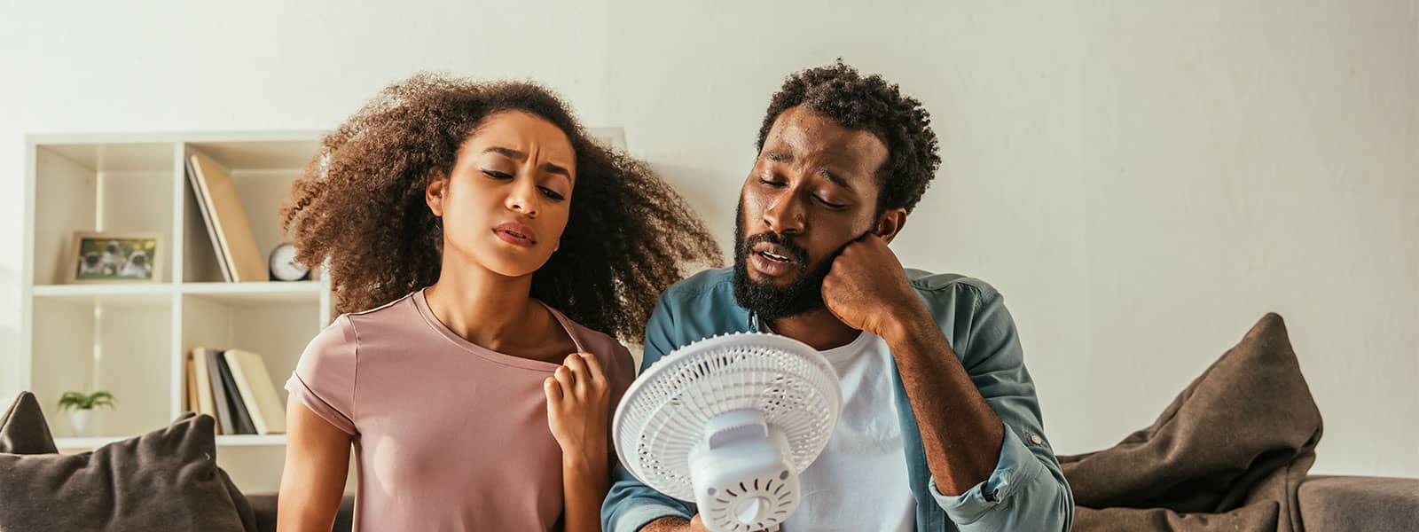 Couple using fan to cool off