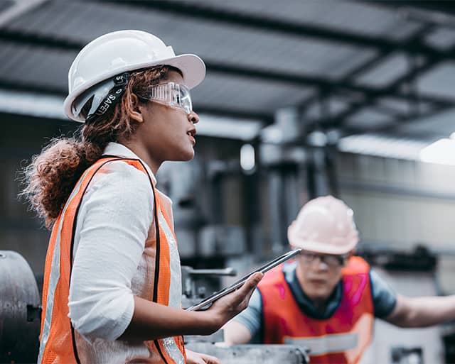 woman in a reflective vest and hardhat with a clipboard