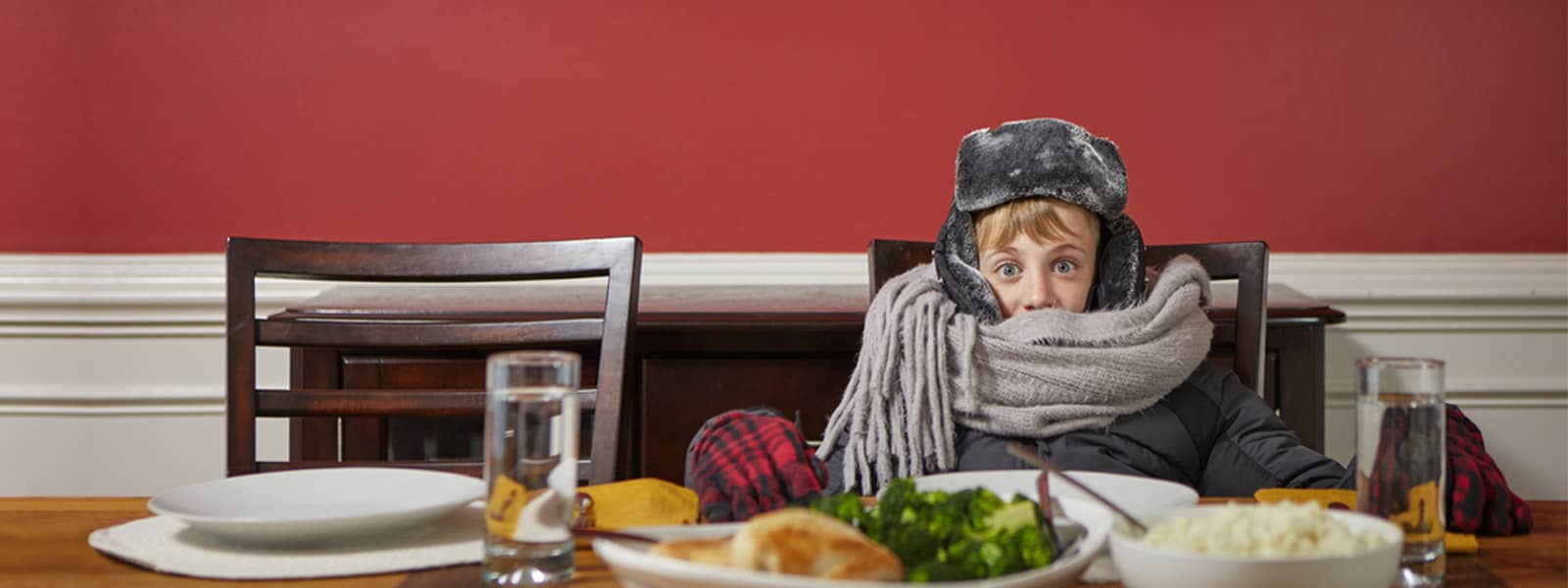 Young boy bundled up for the snow at dinner table