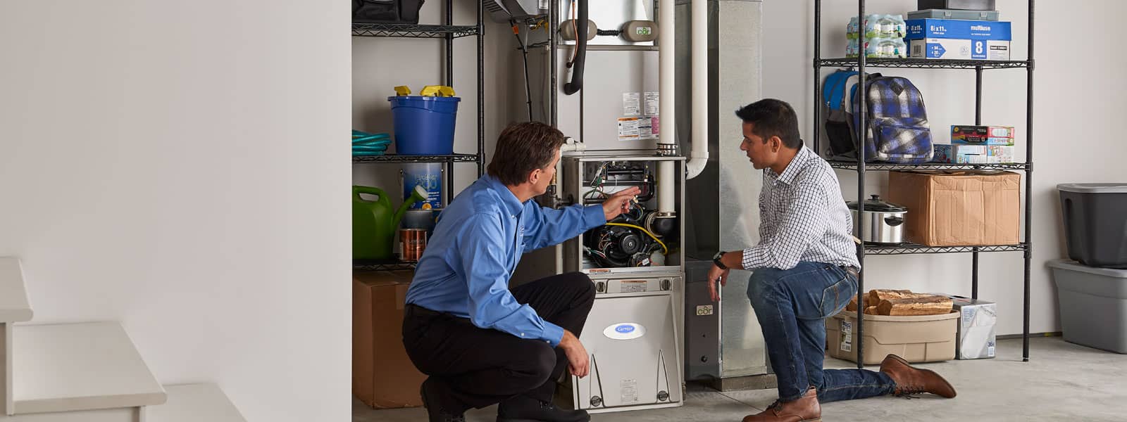 Technician and homeowner looking at new furnace in basement