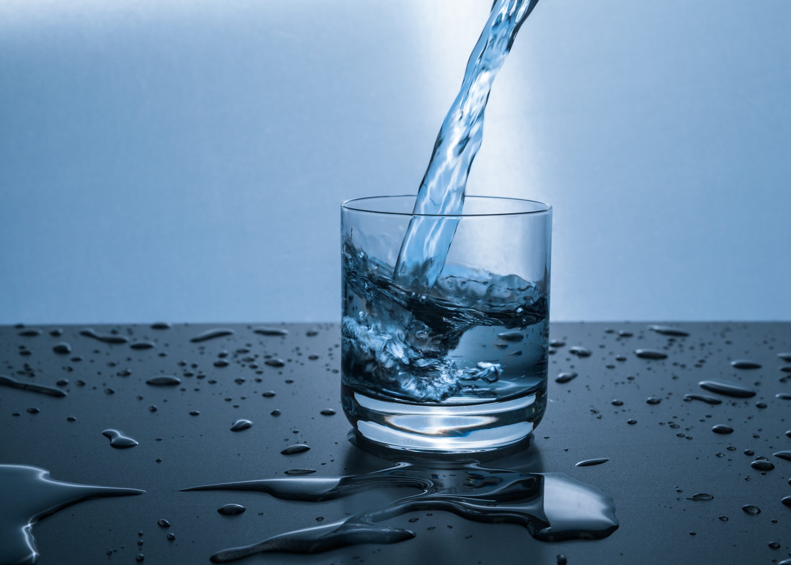 Glass on a table; water pouring into the cup.